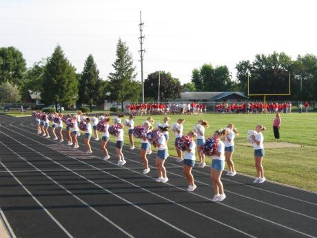 Pom Pons and Cheerleaders lead the audience in the school song