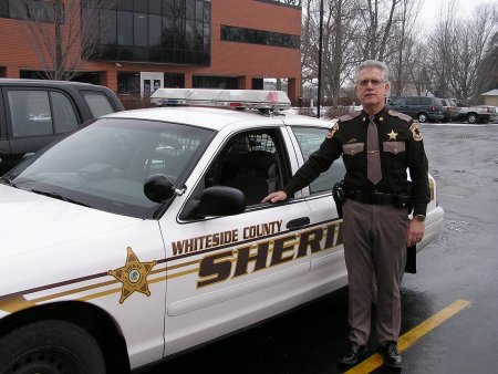 Officer Dick Wieneke stands beside his car at the Law Enforcement Center. Officers are responsible f